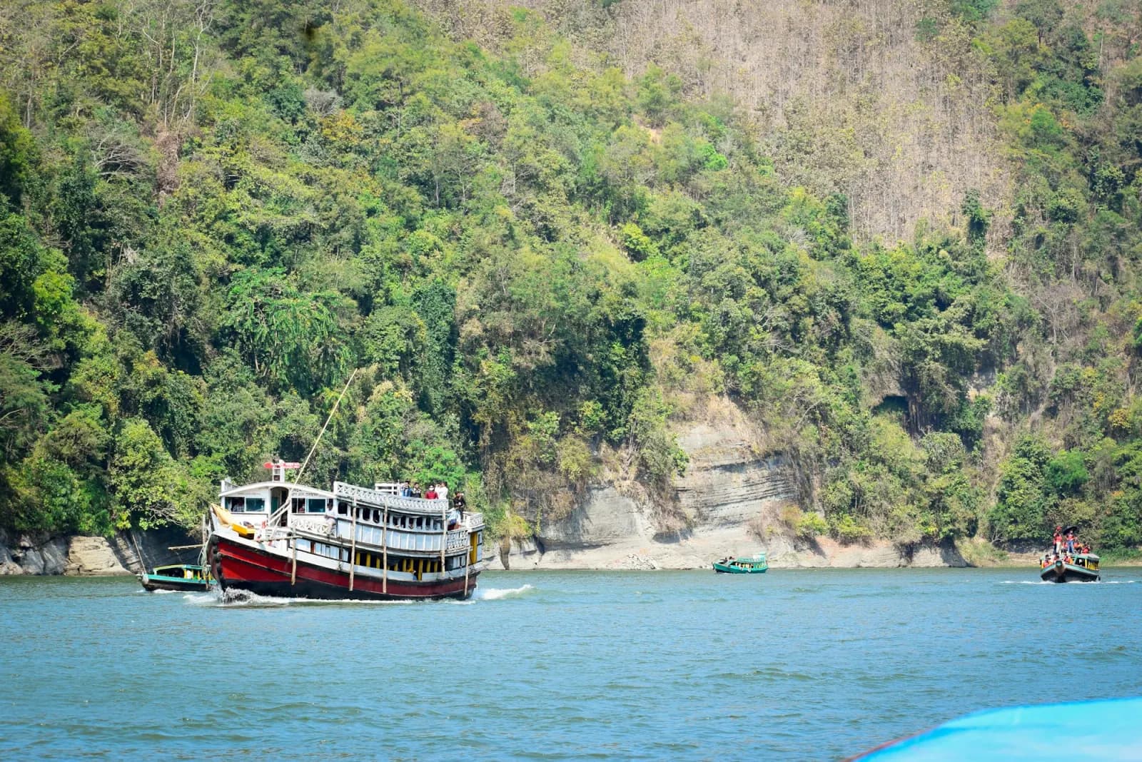 Boat crossing Kaptai Lake beside green hills in Rangamati during the Chittagong Shipyard Tour
